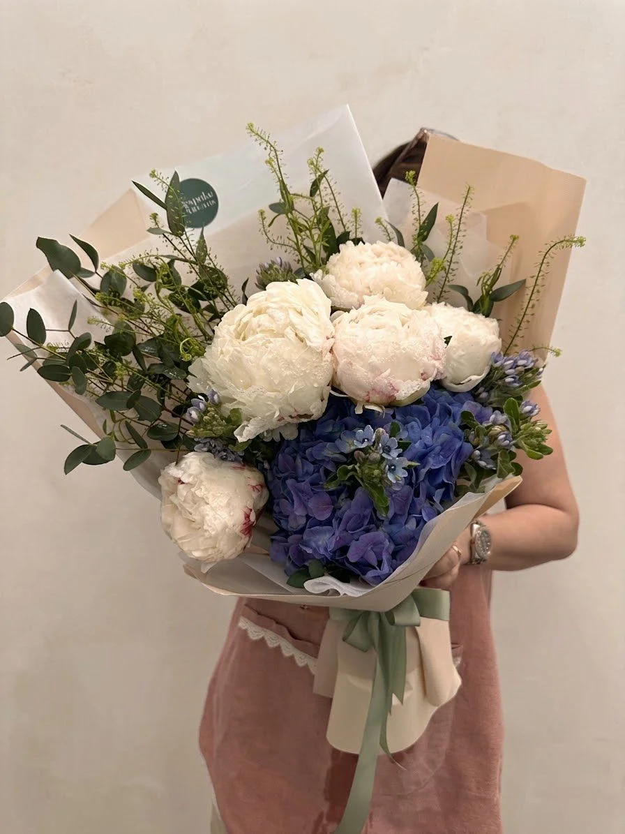 Cream peonies with blue hydrangeas in kraft wrapping