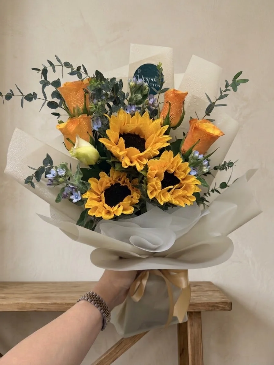 Siena - three sunflowers with orange spray roses, a white rosebud and blue tweedia, in cream and sage wrapping