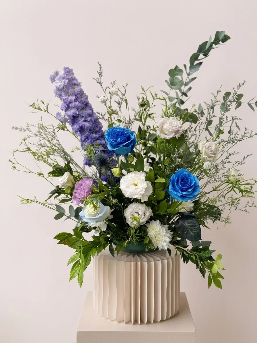 Blue roses, purple delphinium and eucalyptus in a fluted vase
